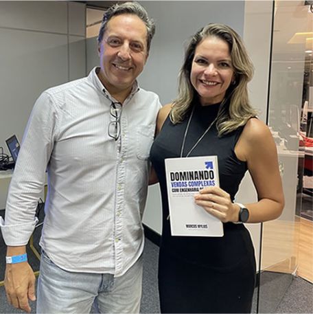 Leitora segurando o livro Dominando Vendas Complexas ao lado de Marcos Mylius