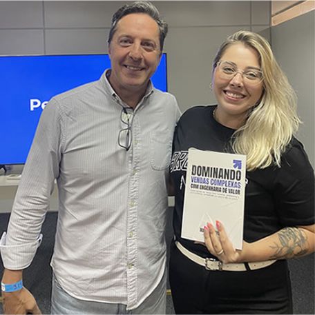 Leitora segurando o livro Dominando Vendas Complexas ao lado de Marcos Mylius