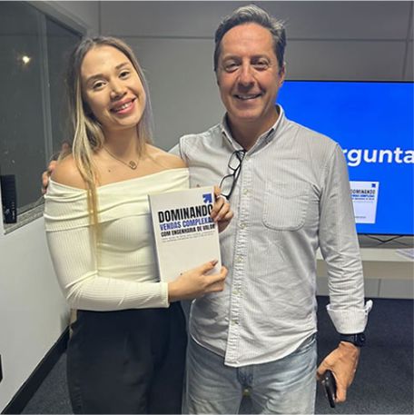 Leitora segurando o livro Dominando Vendas Complexas ao lado de Marcos Mylius