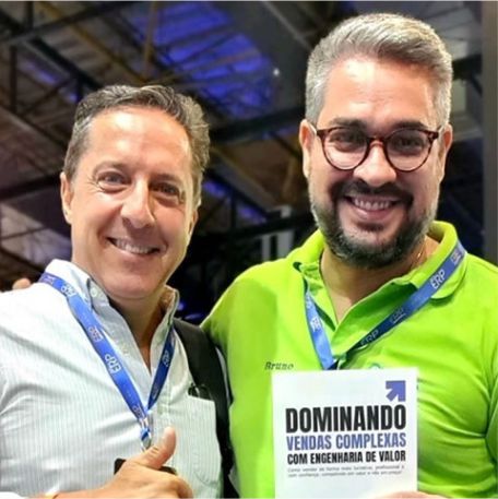 Leitor segurando o livro Dominando Vendas Complexas ao lado de Marcos Mylius