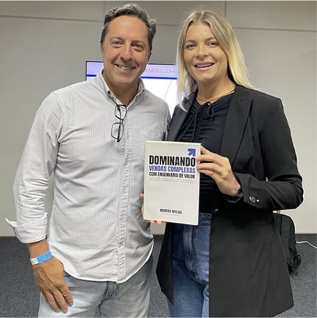 Leitora segurando o livro Dominando Vendas Complexas ao lado de Marcos Mylius