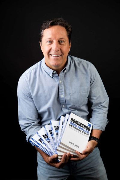 Marcos Mylius, autor do livro Dominando Vendas Complexas Marcos Mylius segurando um leque de exemplares do livro Dominando Vendas Complexas